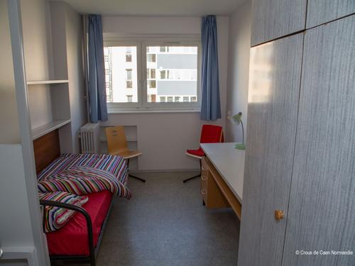 Chambre équipée d'un bureau, d'un lit, d'un placard et d'un lavabo.